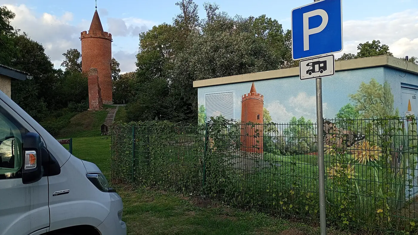 Parkplatzschild mit Zusatzzeichen Wohnmobil am Stellplatz in Putlitz, dahinter ein Turm
